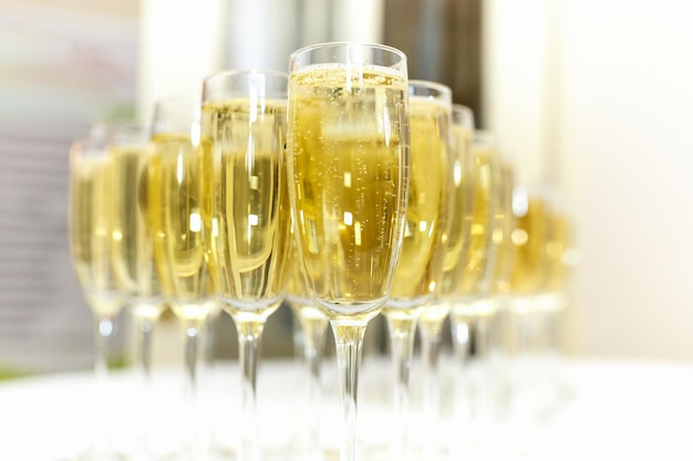 Lot of blurred glasses with champagne on the reception party table on light background