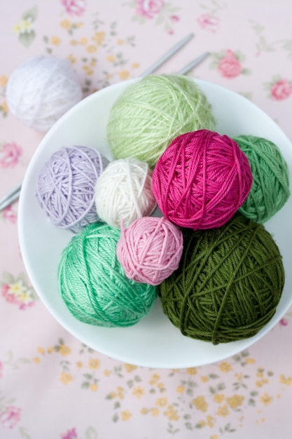 A lot of bright balls of knitting on the background of a pink flower