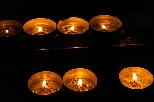 暗闇の寺院にたくさんのろうそくが燃えている宗教の祈りと神の概念