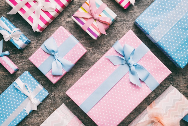 A lot of Christmas gift boxes in colored paper decorated on table Top view close up Many present New Year gift