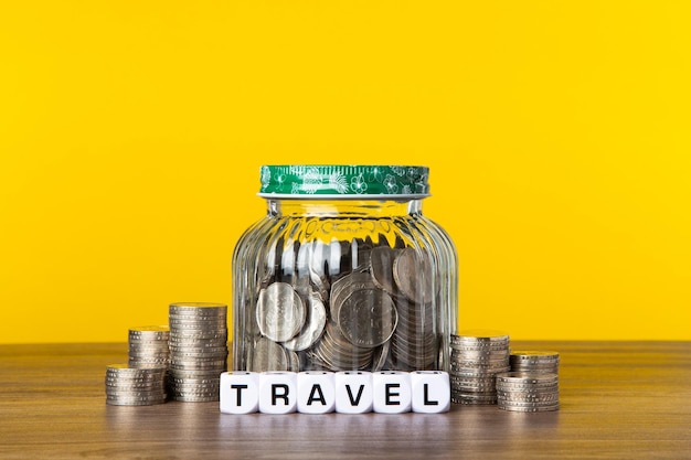 A lot coins in glass jar with yellow background Saving for Travel concept