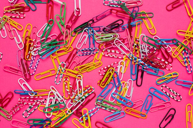 A lot of colored paper clips lie on a pink background. Presentation Slide