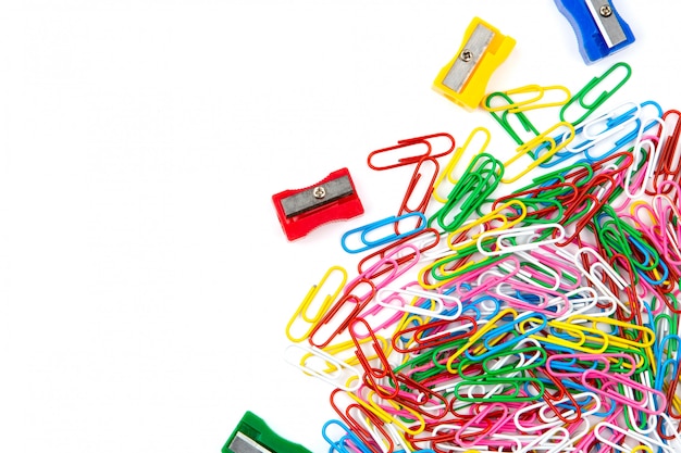 A lot of colored paper clips and pencil sharpeners on a white background. Top view and copy space.