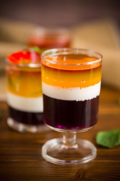 나무 탁자 위에 있는 유리잔에 많은 색깔의 달콤한 과일 젤리