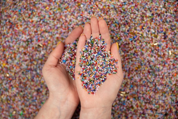 A lot of colorful beads in hands on a white background