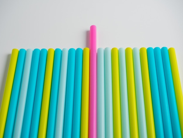 A lot of colorful plastic tubes on a white background top view flat lay one of them is pink in color and is pushed forward the chosen one the special one stands out from the crowd