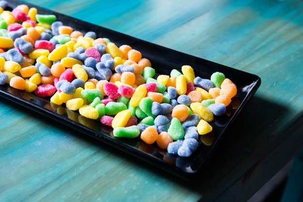 Un sacco di caramelle gommose colorate, caramelle e caramelle, in un vassoio nero sul tavolo, a una festa di compleanno.