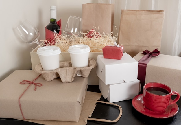 A lot of Craft Paper Bags and Boxes, wine bottle and cups of coffee on the table, delivery concept.