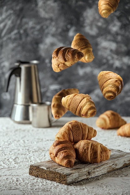 a lot of croissants in flight food levitation croissants on a white table and a coffee maker