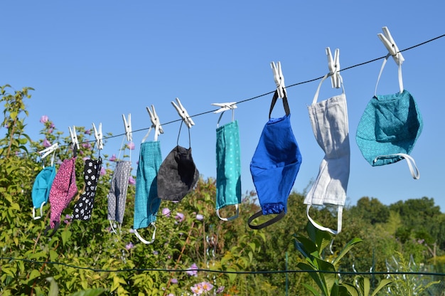 Photo a lot of different colorful self made corona face masks out of fabric hanging on clothesline drying