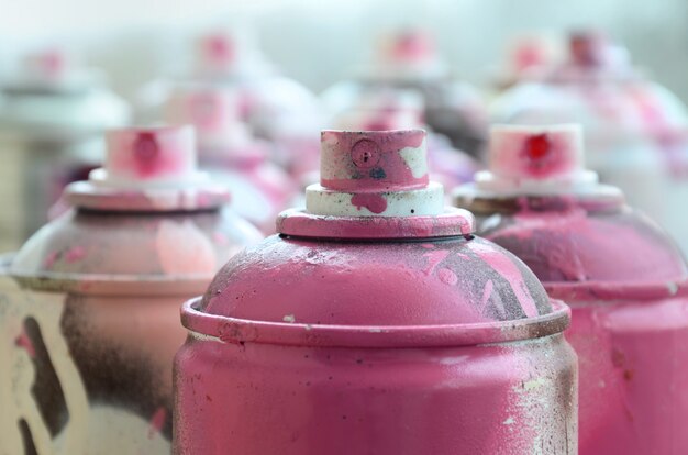 Un sacco di bombolette aerosol sporche e usate di vernice rosa brillante.