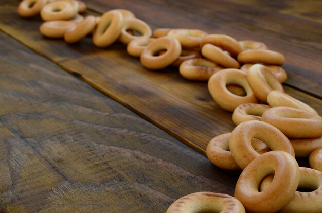 A lot of fresh yellow bagels lie on the surface of the old dark wood