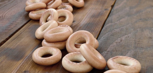 A lot of fresh yellow bagels lie on the surface of the old dark wood