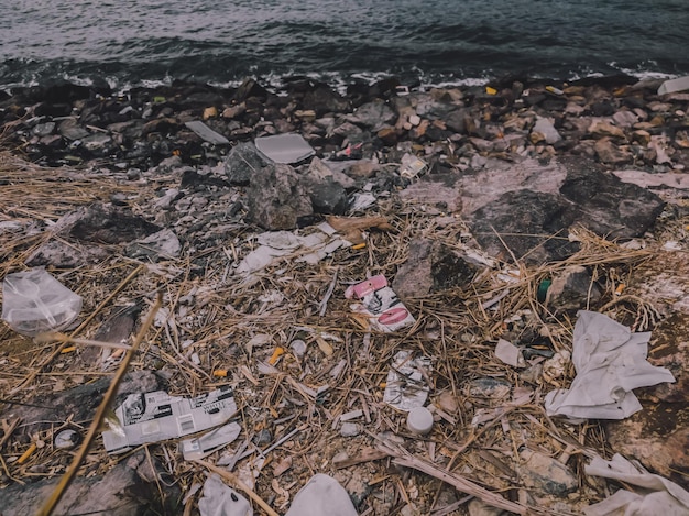 땅에 흩어져 있는 많은 쓰레기 해변의 바다 근처 쓰레기 환경 재해 및 오염의 문제 지구 생태학 쓰레기의 무단 투기