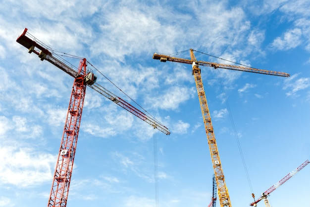 Lot of high tower cranes work on the construction of new buildings. Wide angle.