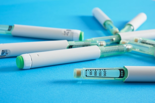 A lot of insulin syringe pens for diabetes treatment on blue background