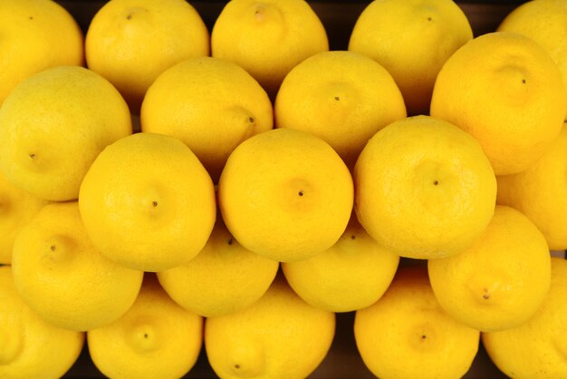 A lot of juicy colorful lemons in the box. Lemons background.