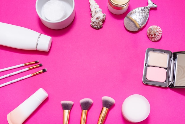 Lot of make up on pink background, copy space