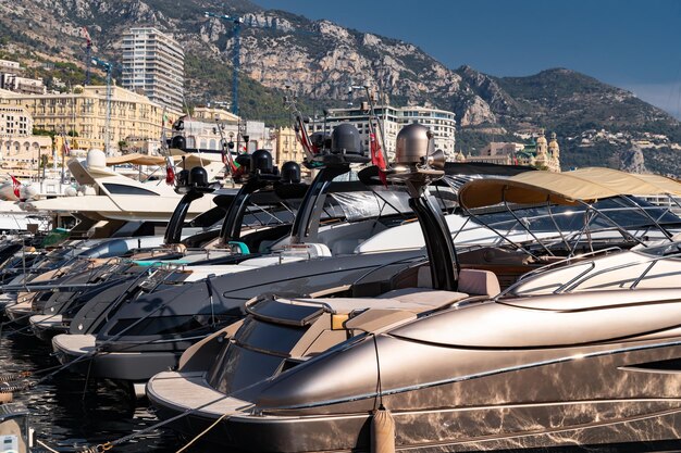 A lot of motor boats in rows are in port of monaco at sunny day monte carlo mountain is on backgroun...