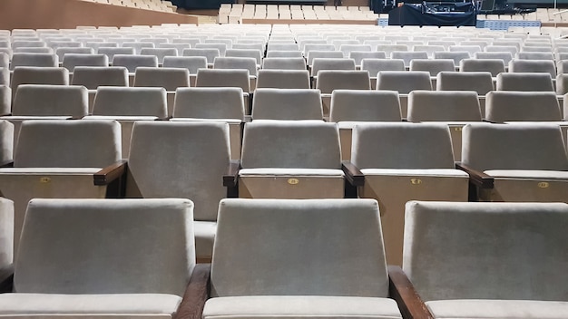 A lot of old beige upholstered chairs without people in the hall for performances and films. Background from many chairs in the stands in a concert hall or theater.