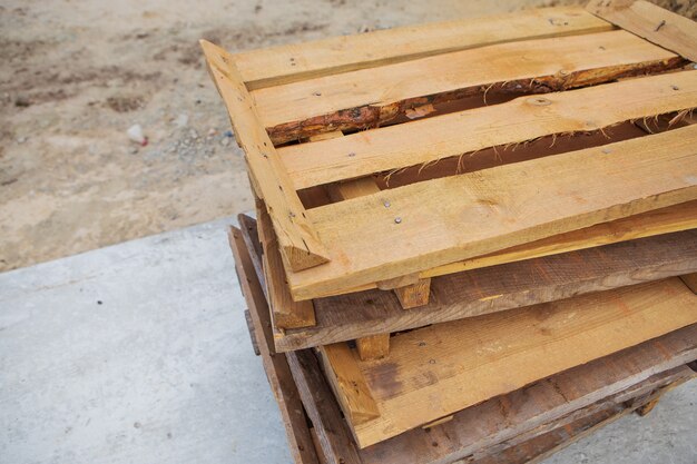 Molti vecchi pallet di legno stanno sulla strada uno sopra l'altro, tutti per la riparazione.