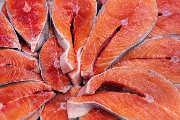 Lot of pieces raw Pacific Red Fish Chinook Salmon cut into steak and ready for cooking various delicious dishes. Close-up flat lay view of fresh wild fish King Salmon - delicacy Asian cuisine.