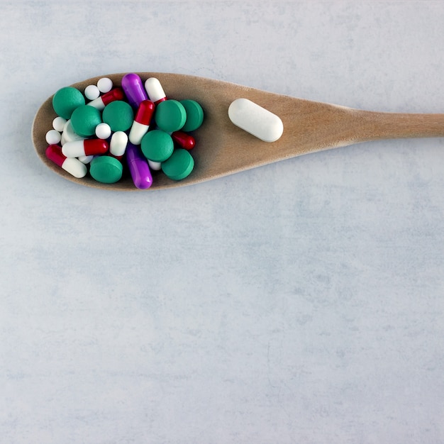 Lot of pills and  vitamins in a wooden spoon 