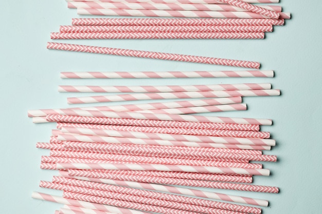 A lot of pink paper straws on a blue background. Top view. Place for text.