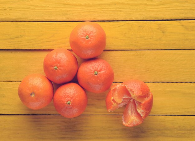 A lot of ripe tangerines on a yellow wooden table