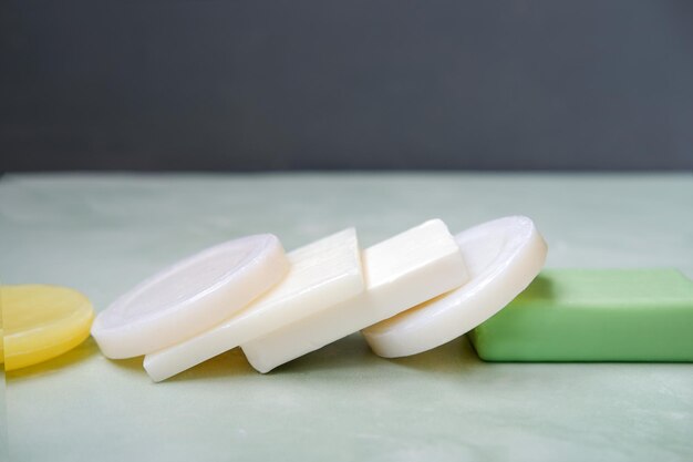 A lot of soap bars like after domino effect lies on bathroom\
tile against grey wall