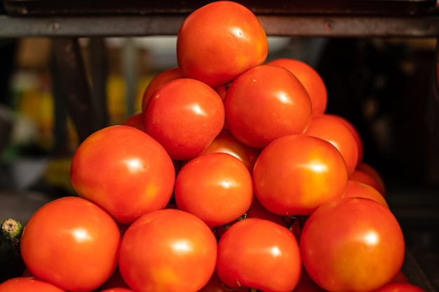 Molti pomodori giacciono uno sopra l'altro a forma di piramide alla luce del sole