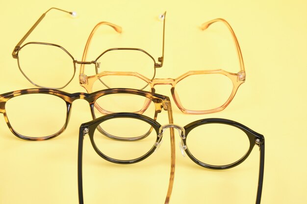 A lot of trendy trendy eyes glasses for vision correction on a yellow background copy space