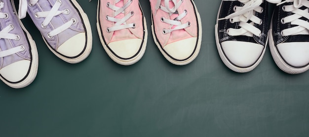 Foto un sacco di scarpe da ginnastica in tessuto usate su sfondo verde, varie dimensioni. concetto di famiglia, amicizia, vista dall'alto, copia spazio