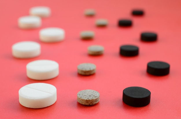 Много красных, черных и коричневых таблеток лежат на красной поверхности