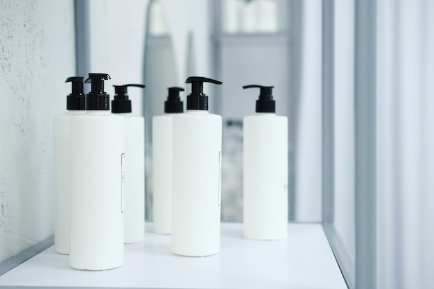 A lot of white cosmetic jars are on a shelf in a beauty specialist's office