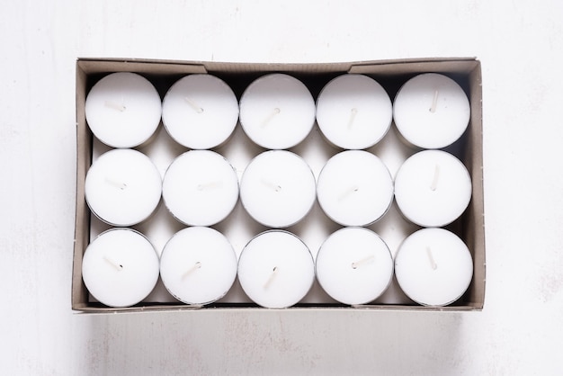 Photo lot of white tealight candles in bulk in carton packing box