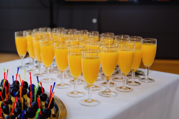 A lot of wine glasses with orange juice on the table at the ceremony Selective focus Closeup