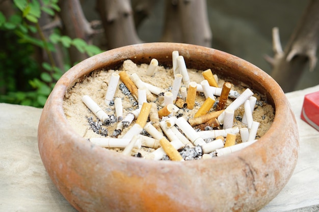 Lots of cigarette butts in a sandbox Polluted environment and dangers for children