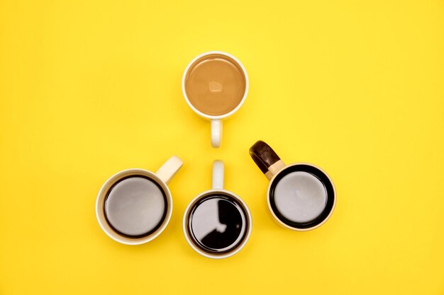 Lots of coffe cups wth different cups of coffee on yellow background Trendy concept top view