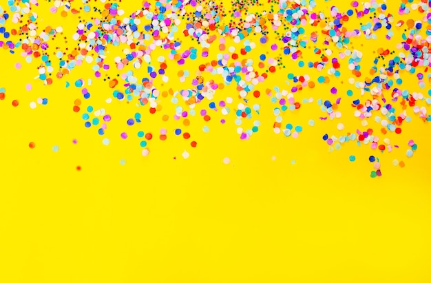 Premium Photo | Lots of colored confetti on a yellow background.