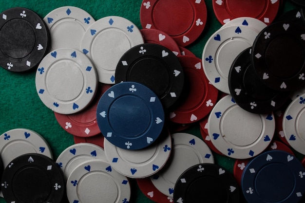 Lots of colorful casino poker chips lie on a green velvet gaming table. Background for gambling.