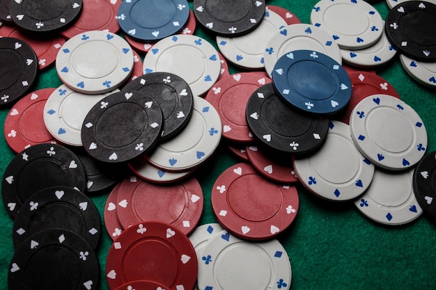 Lots of colorful casino poker chips lie on a green velvet
gaming table. background for gambling.