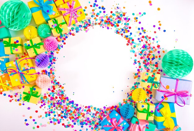 Lots of colorful gift boxes and colorful confetti on a white background. Top view