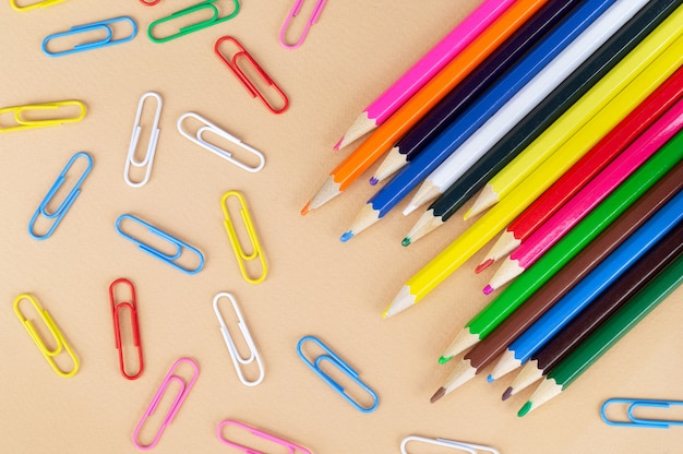 Lots of colorful pencils and paper clips, top view