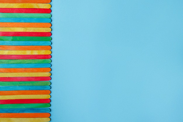 Lots of colorful wooden ice cream sticks on a blue background