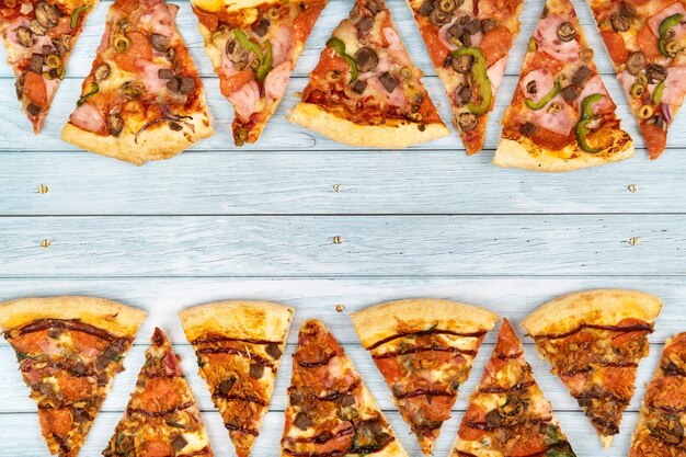 Lots of delicious triangular pizza slices on a blue wooden background.