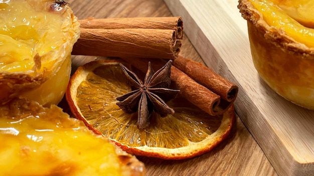 Foto molti dessert pastel de nata o torta d'uovo portoghese e bastoncini di cannella pastel de belm è una piccola torta con una crosta di pasticceria croccante e un ripieno di crema di crema