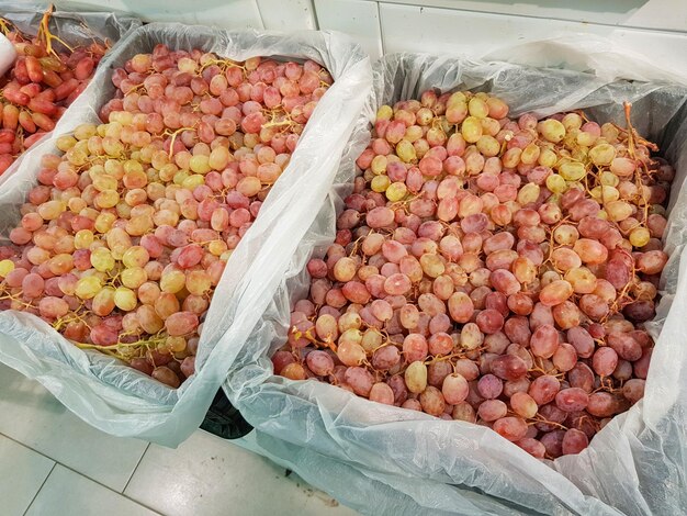 Photo lots of fresh ripe red grapes in containers on the market closeup