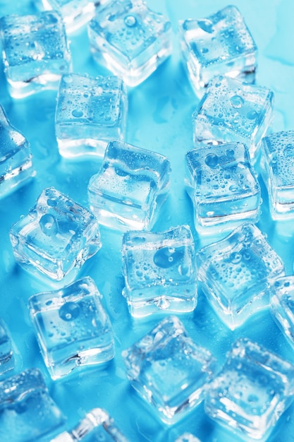 lots of ice cubes with water drops scattered on a blue background top view