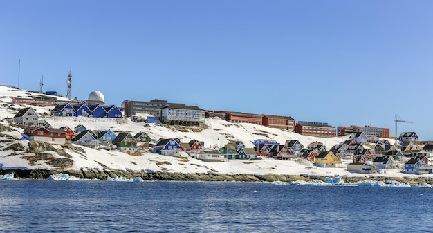 Lots of Inuit huts and living buildings scattered on the rocky coast along the fjord Nuuk city Greenland